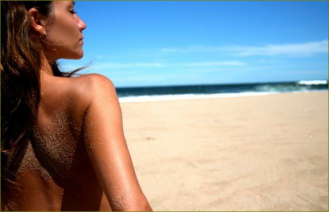 Djevojka se sunča na plaži uz pomoć proizvoda za sunčanje