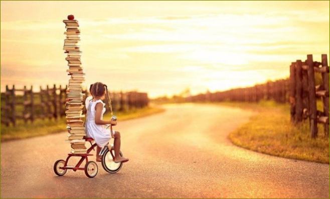 Djevojka na biciklu s planinom knjiga pri zalasku sunca